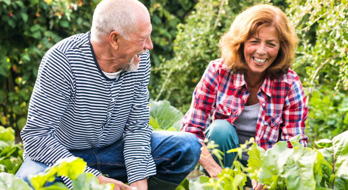 An older adult in a garden, pausing mid-motion